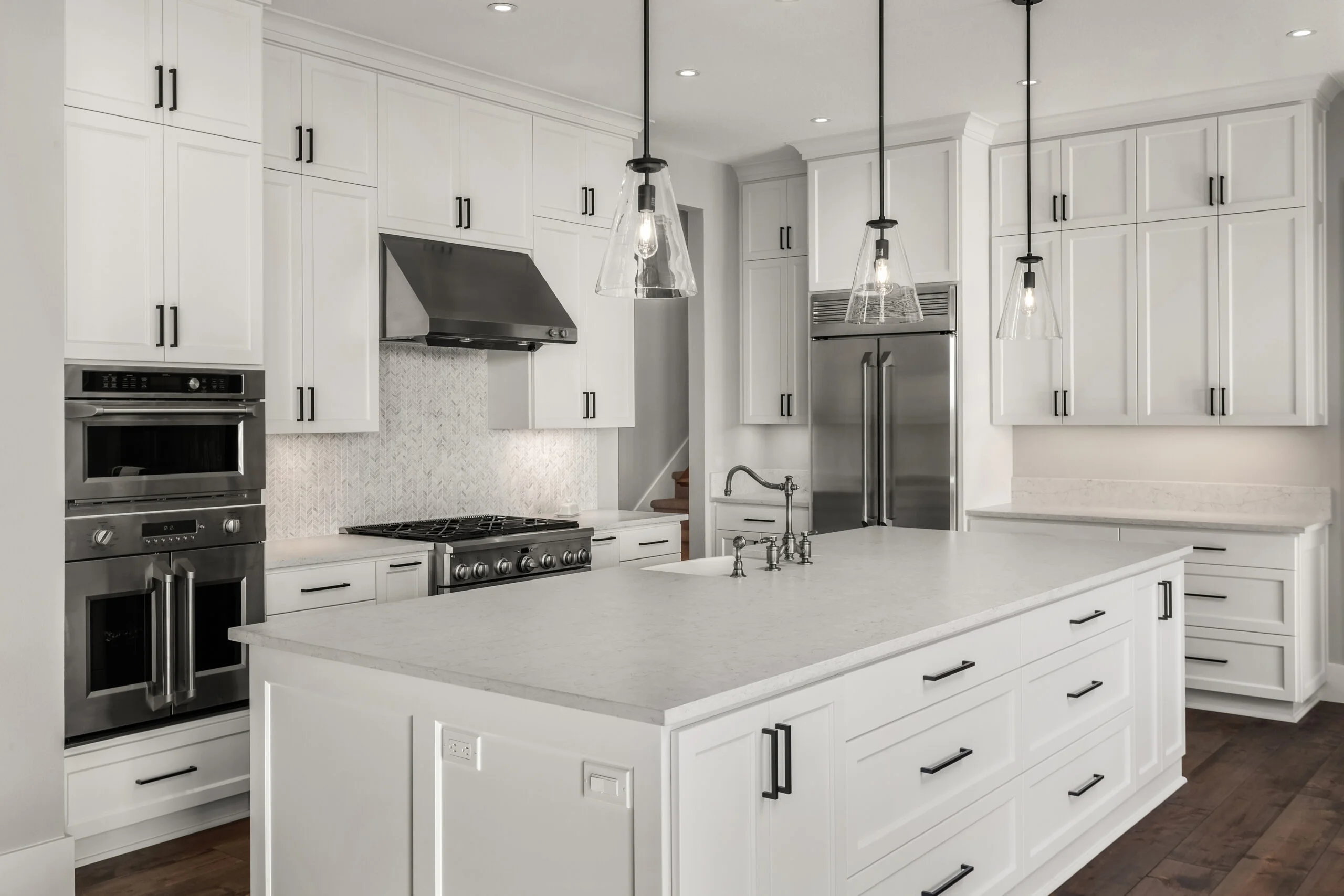 Custom kitchen with white cabinetry with a large white island, stainless steel appliances and pendant lighting designed by Kitchen Remodeling Company San Francisco, Front Street Builders
